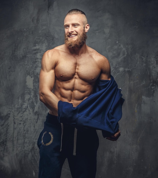 Smiling muscular man taking of his sports sweater.