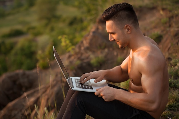 Smiling muscular man with laptop outdoor