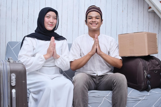 Smiling muslim couple showing hands apologizing or welcoming home with suitcases and cardboard boxes