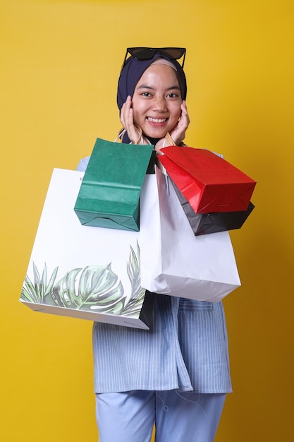 캐주얼한 스타일의 웃는 이슬람 소녀는 많은 종이 가방을 들고 쇼핑하는 것을 좋아합니다.