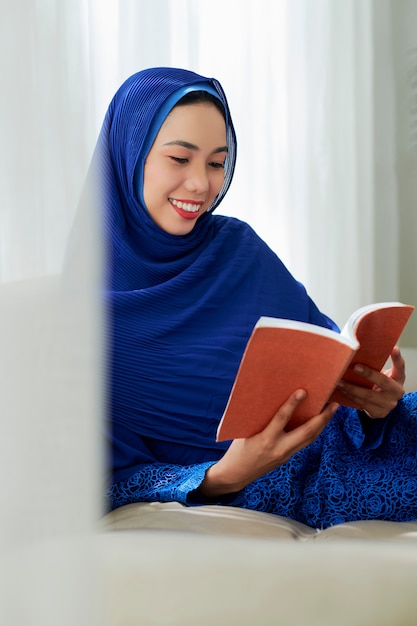 Photo smiling muslim woman reading book