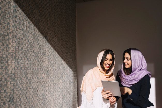 smiling muslim women with tablet