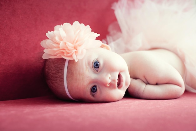 Photo smiling newborn baby girl with a flower in her hair