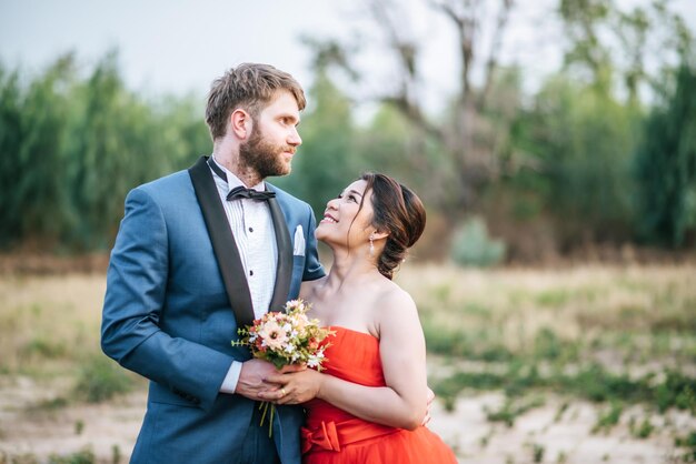 Smiling newlywed couple standing on field