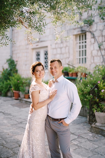 Smiling newlyweds stand in the courtyard of a house on paving stones