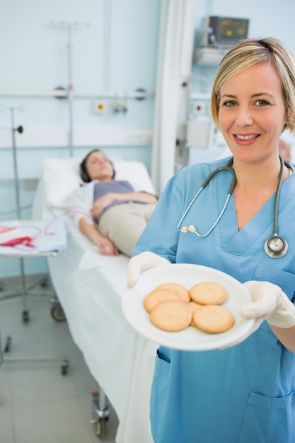 Smiling nurse holding a biscuits plate