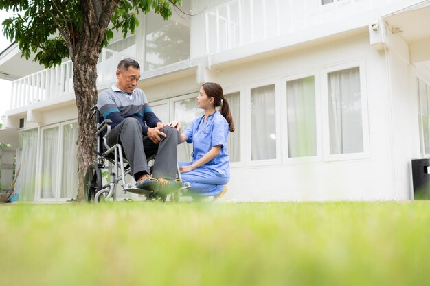 Smiling nurse and senior man sitting in a wheelchair in the garden