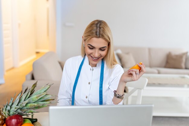 Nutrizionista sorridente nel suo ufficio sta mostrando frutta e verdura sane concetto di assistenza sanitaria e dieta nutrizionista femminile con frutta che lavora alla sua scrivania