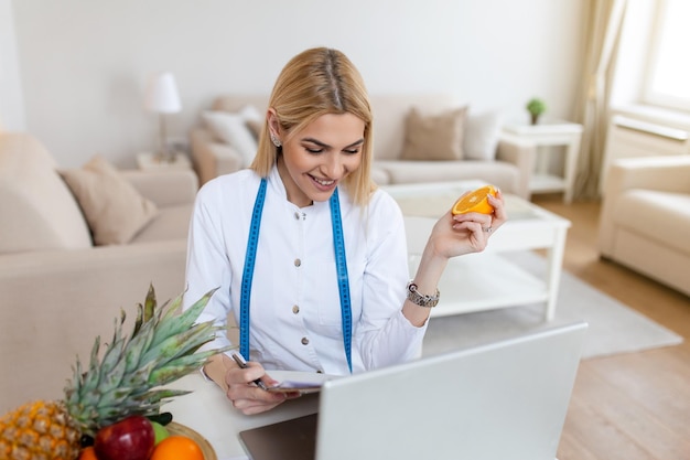 Nutrizionista sorridente nel suo ufficio sta mostrando frutta e verdura sane concetto di assistenza sanitaria e dieta nutrizionista femminile con frutta che lavora alla sua scrivania