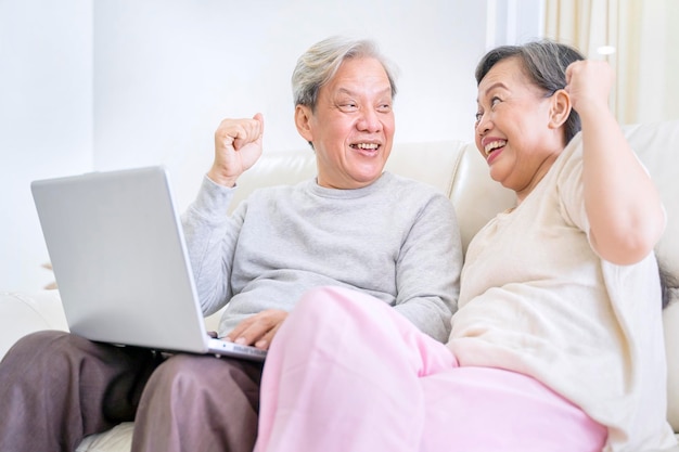 집에서 노트북을 사용하여 웃고 있는 노부부