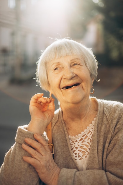 Smiling old grandmother with gray hair and a positive smile while walking in the evening city