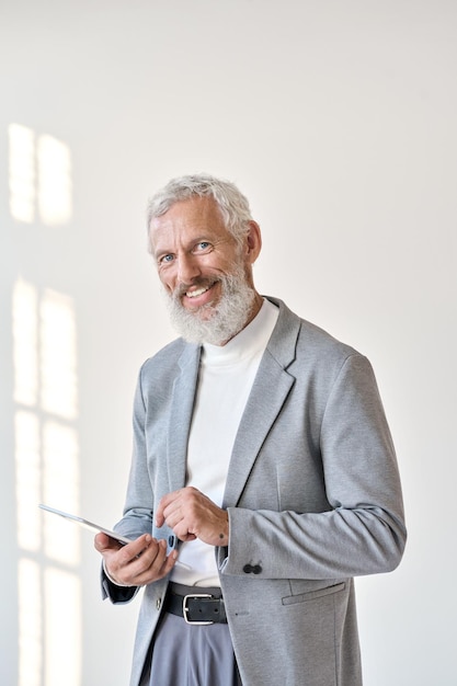 Smiling old senior businessman using tablet isolated on white wall vertical