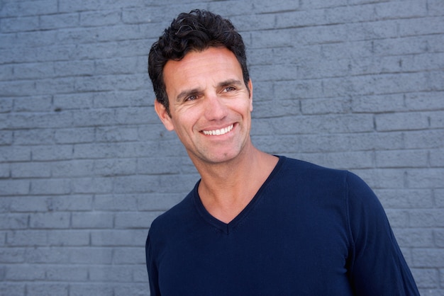 Smiling older man standing against gray wall