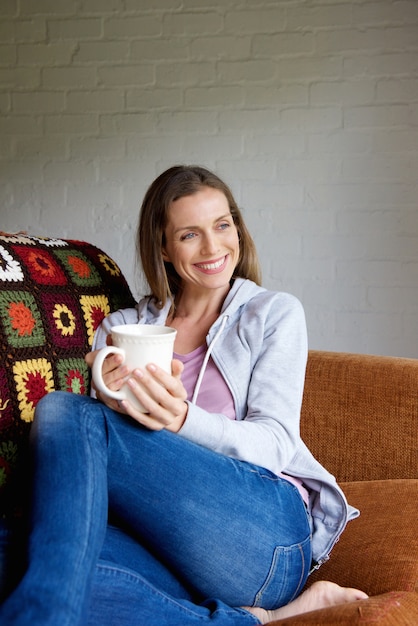 Smiling older woman sitting with cup of tea at home