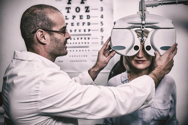 Smiling optometrist examining female patient on phoropter