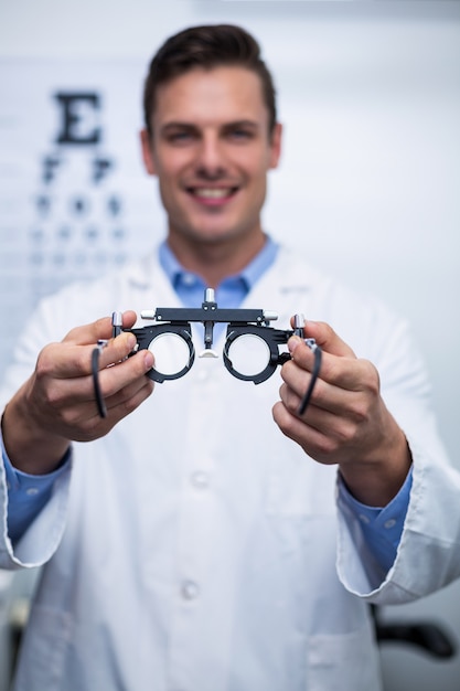 Smiling optometrist holding messbrille