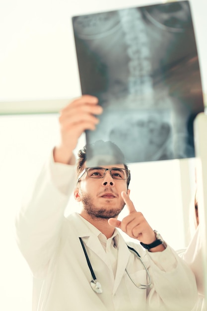 Улыбающийся врач-ортопед смотрит на рентгеновский снимок пациента. Фото с копией пространства
