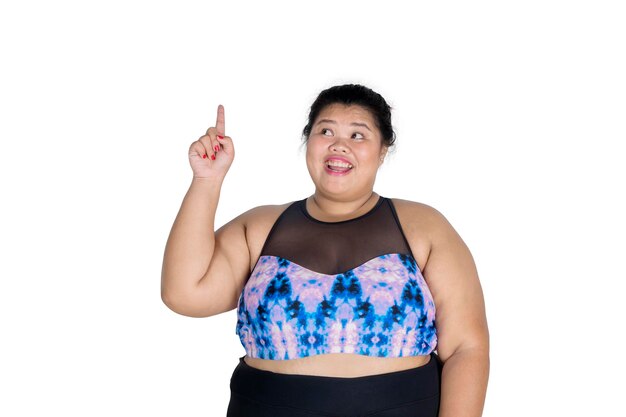 Photo smiling overweight woman pointing while standing against white background