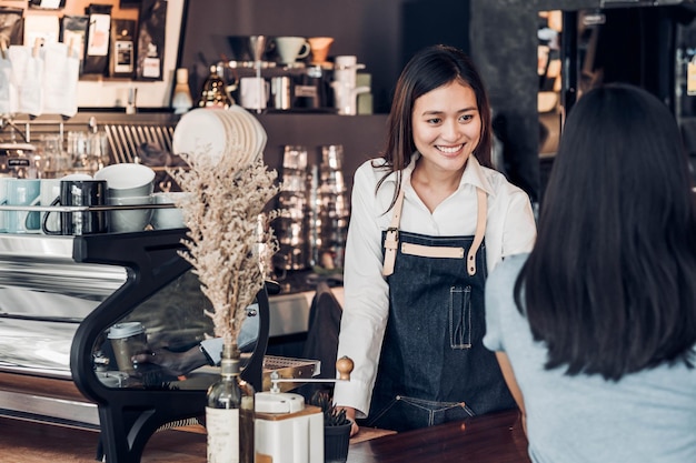 smiling owner talking to customer while standing at counter in cafe