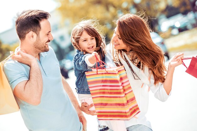 Photo smiling parents and daughter with shopping bags