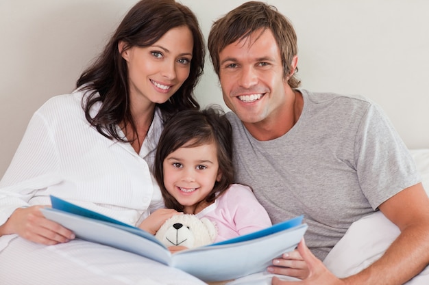 Smiling parents reading a story to their daughter