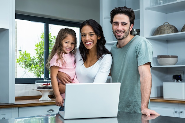 Smiling parents using laptop with daughter