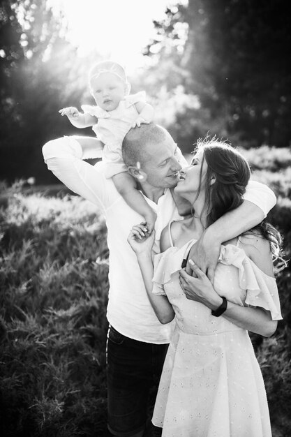 Photo smiling parents with cute baby girl young family walking at the park smiling adorable daughter