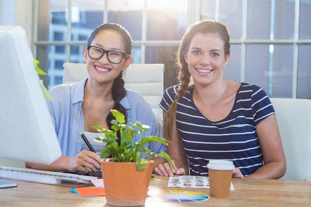 Smiling partners working together with photographs and digitizer in the office