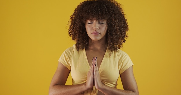 Smiling peaceful young woman practicing yoga and meditation. Calm woman making Namaste gesture and looking at camera. Yoga concept. Gratitude.