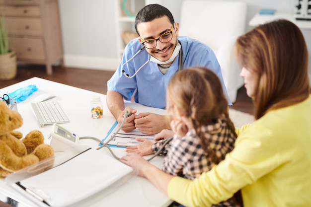 Smiling Pediatrician Talking to cute with Little Girl