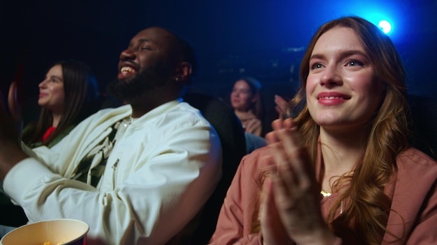 Smiling people having fun in cinema Cheerful group applauding in dark hall