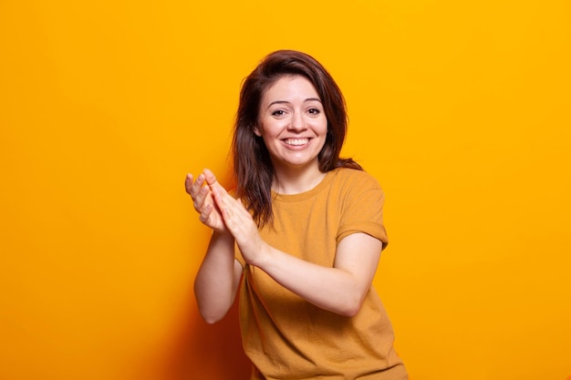 Smiling person clapping hands to celebrate achievement, looking at camera. Positive woman applauding and doing appreciation gesture to approve on presentation. Proud adult acclaiming