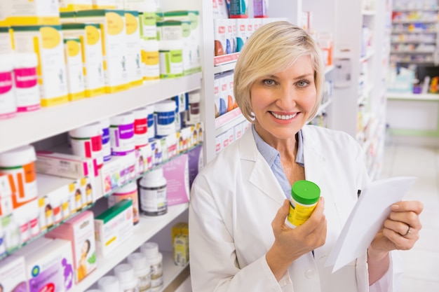 Smiling pharmacist holding prescription and medicine