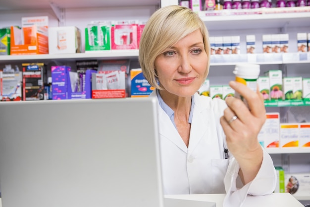 Smiling pharmacist looking at medicine