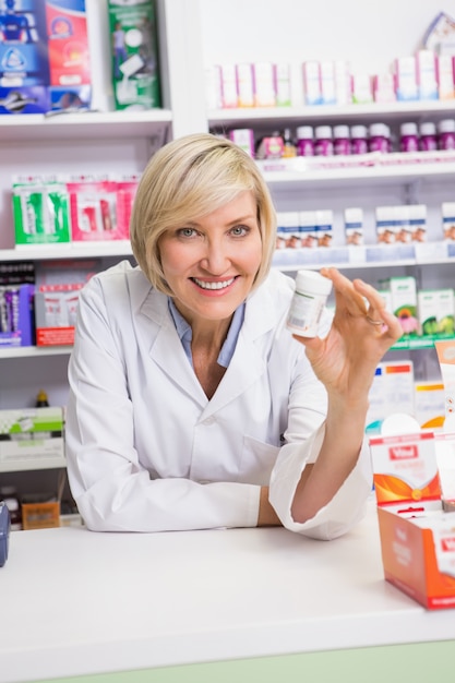 Smiling pharmacist showing medication 