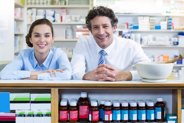 Foto farmacisti sorridenti che si appoggiano al contatore in farmacia