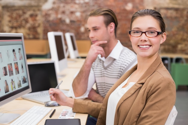 Smiling photo editors using computer in office