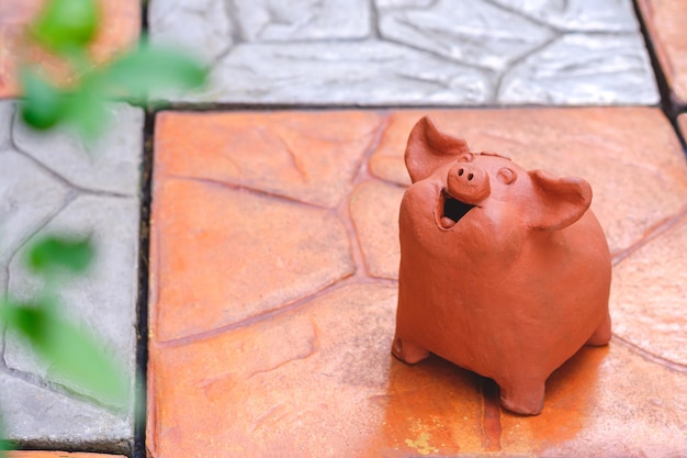 Smiling pig terracotta garden doll on stone tile pavement floor in home garden