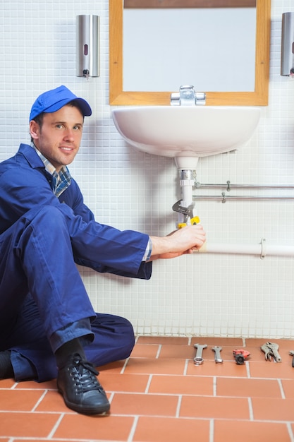 smiling plumber repairing sink