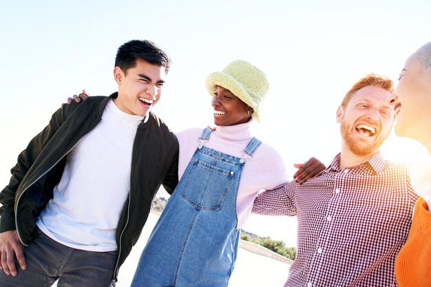 Smiling portrait of cheerful group multiracial friends looking at each other outdoors spring day