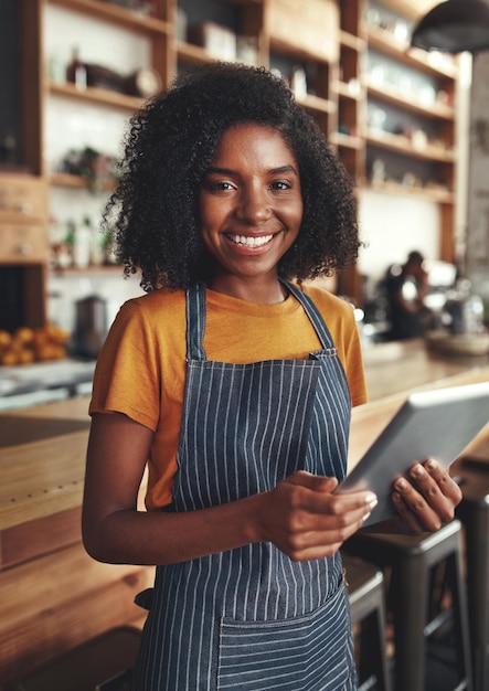 smiling portrait of a female owner holding digital tablet in her