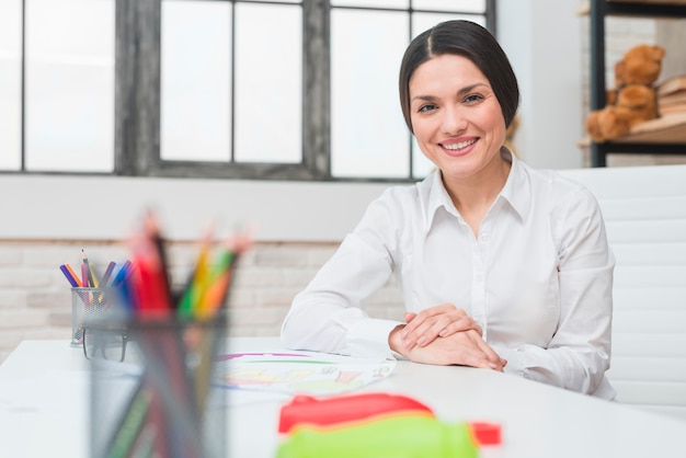 Smiling portrait of a young confident female psychologist sitting in her office