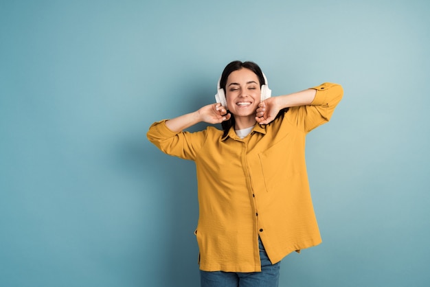 A smiling, positive girl in wireless headphones listens to music