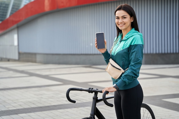 Smiling positive lady demonstrating smartphone in the city