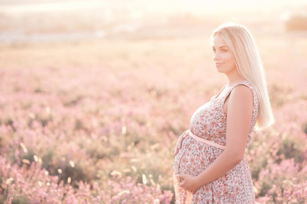 Smiling pregant woman in lavender flowers meadow