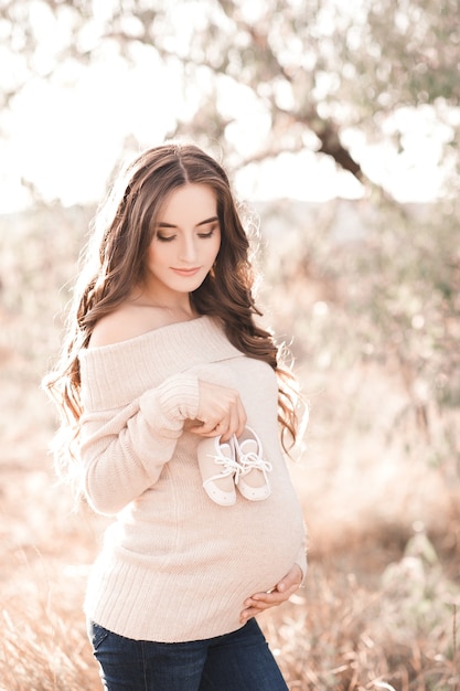 Smiling pregnant woman holding baby boots