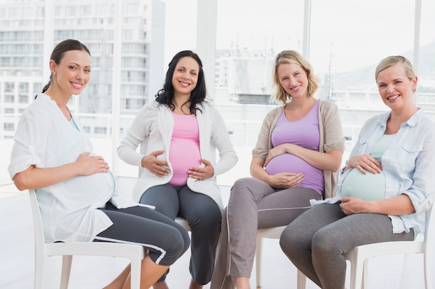 出産前のクラスで一緒に座っている妊娠中の女性を笑顔
