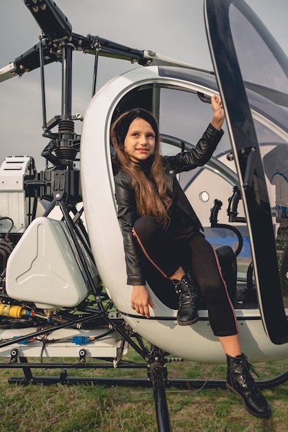 Smiling preteen girl sitting in open cockpit of helicopter