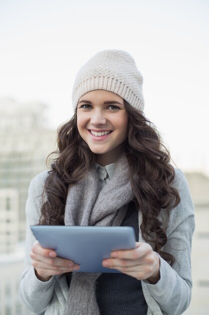 Smiling pretty brunette holding her tablet