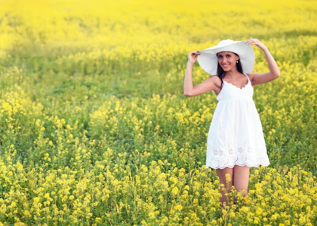 Smiling pretty girl in white in blooming field